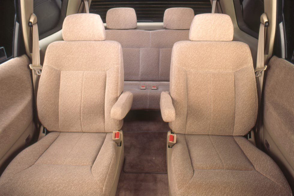 Interior view of a vehicle showing four fabric-covered seats arranged in two rows.