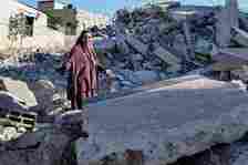 The mother of Ahmed Dawabsha walks on the rubble of her house in the village of Duma in the occupied West Bank