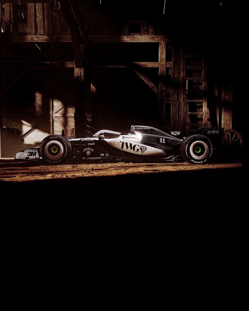 Cadillac F1 car number 11 in a black and silver cowboy-inspired livery, shown in a dim wooden barn at the United States Grand Prix