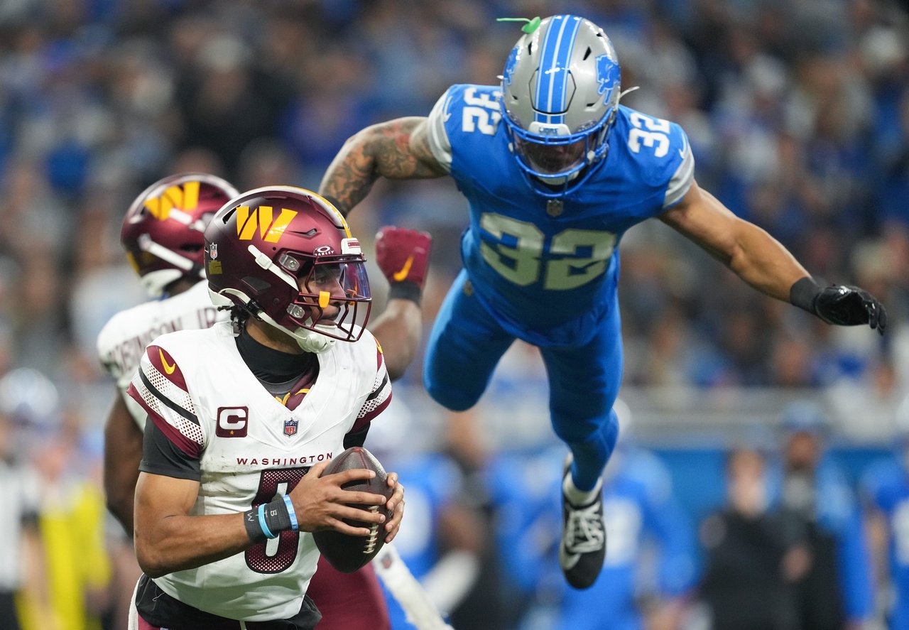 DETROIT, MICHIGAN - JANUARY 18: Jayden Daniels #5 of the Washington Commanders scrambles with the ball as Brian Branch #32 of the Detroit Lions dives to apply pressure during the third quarter in the NFC Divisional Playoff at Ford Field on January 18, 2025 in Detroit, Michigan. 