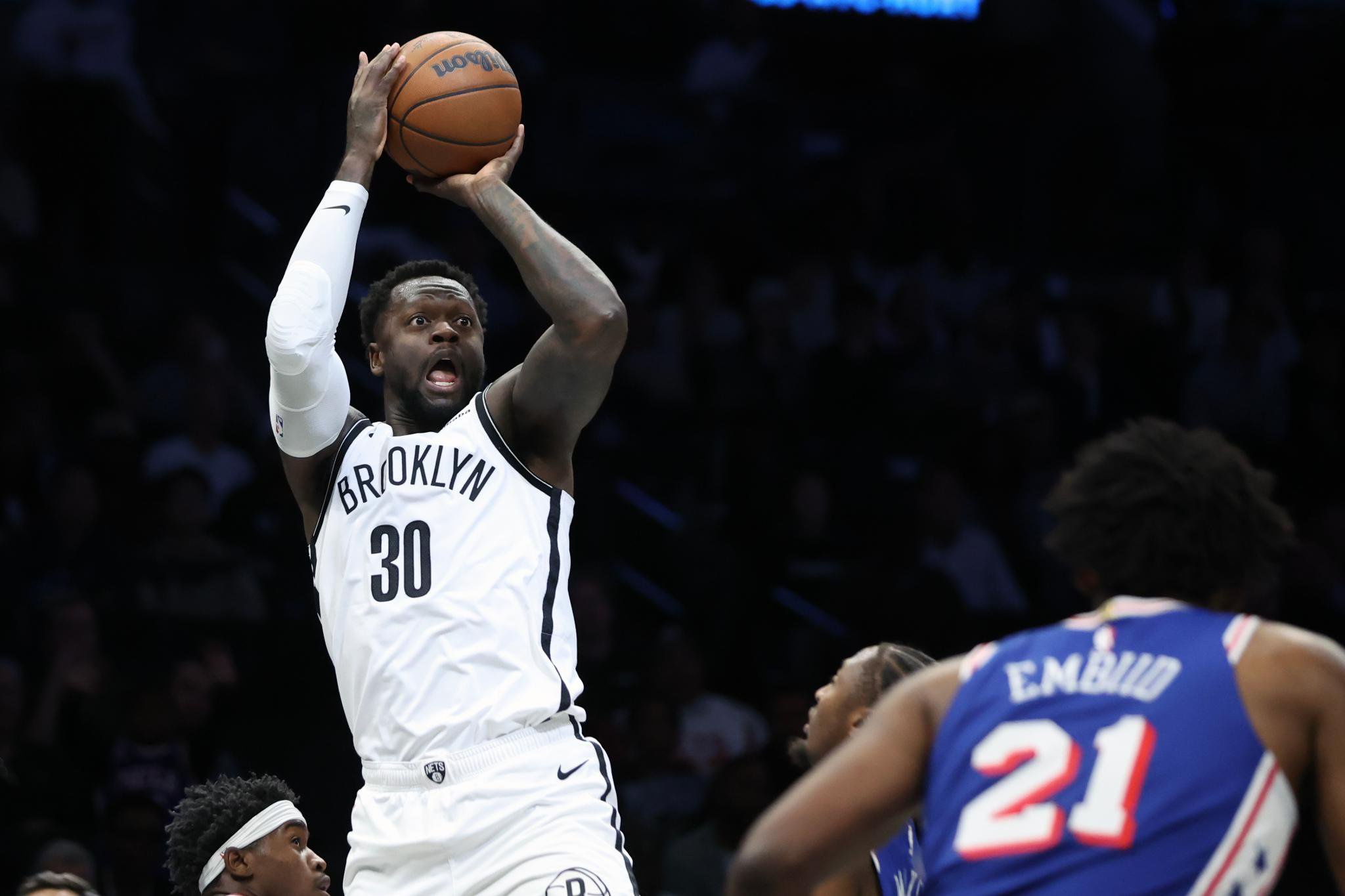Brooklyn Nets forward Julius Randle shoots over Philadelphia 76ers defenders during a preseason NBA game.