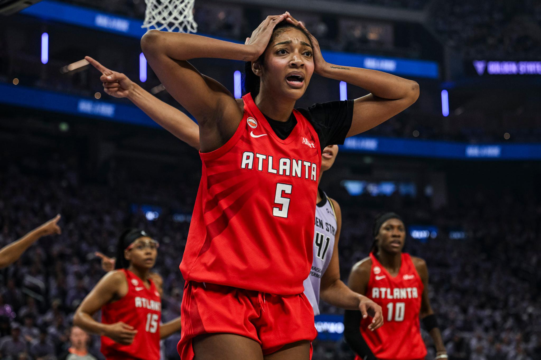 Angel Reese wearing an Atlanta jersey with her hands on her head on a basketball court.