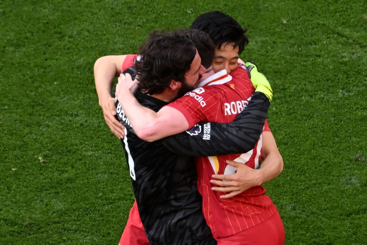 Alisson Becker and Wataru Endo of Liverpool celebrate the teams victory and confirmation of winning the Premier League title after the Premier League match between Liverpool FC and Tottenham Hotspur FC