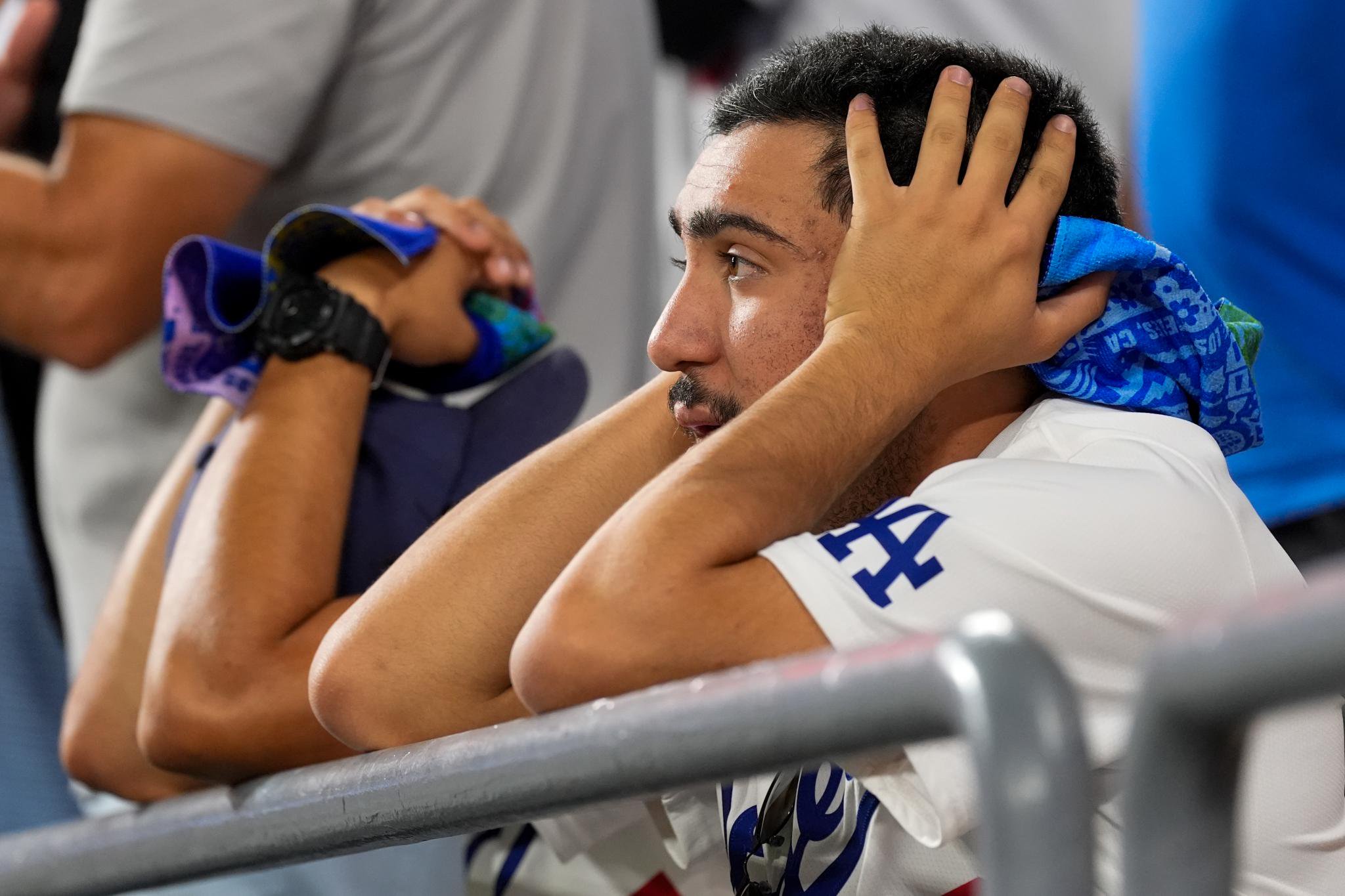 A distressed Los Angeles Dodgers fan holds his head in his hands during a baseball game.