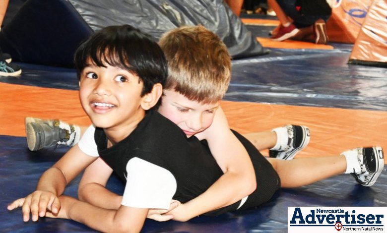 Two young children are photographed on the wrestling mat.