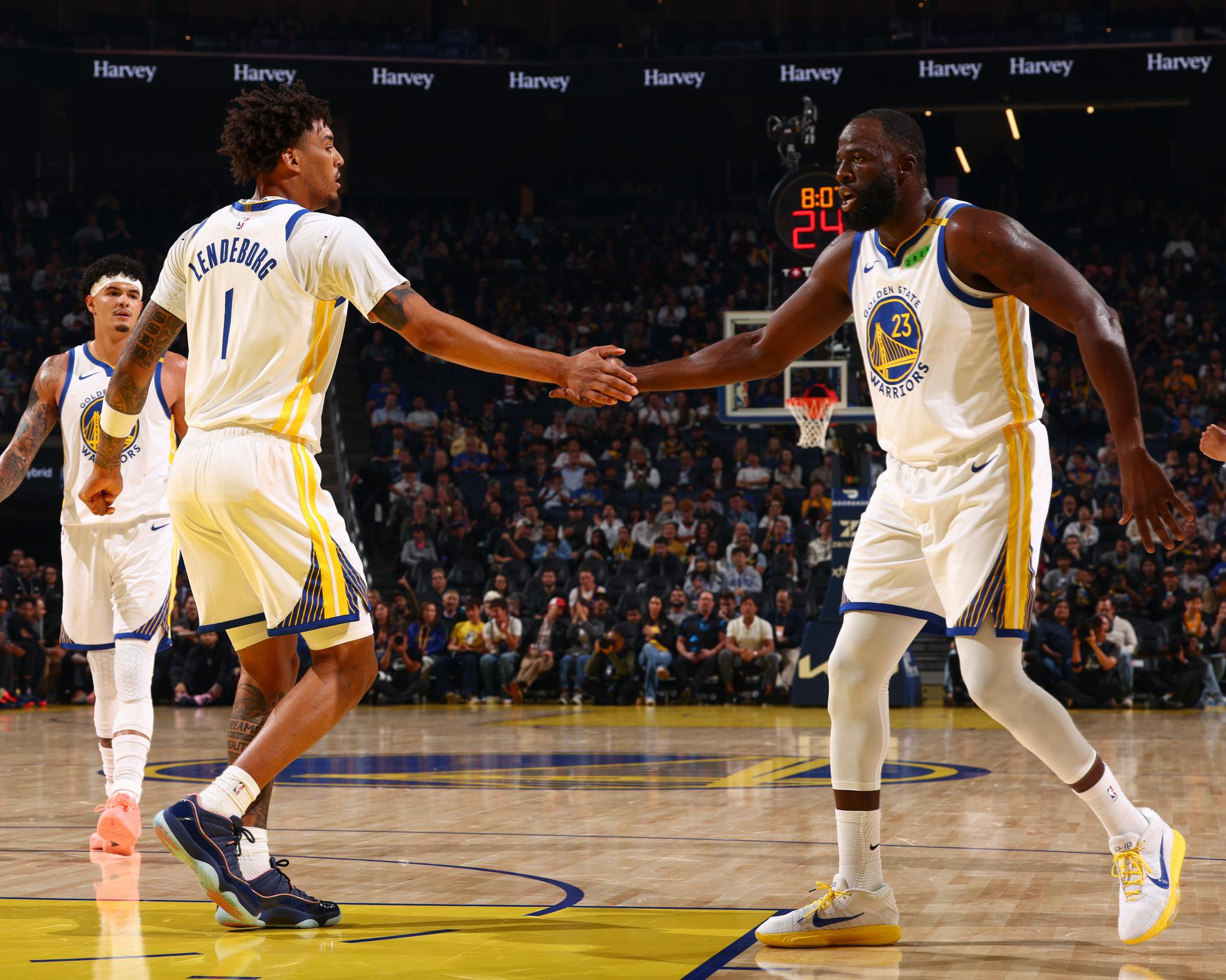 Golden State Warriors players Draymond Green and a teammate shake hands on the court during a game against the Sacramento Kings.