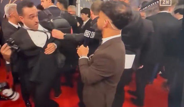 A photographer was seen clashing with a security guard on the event's official broadcast after he was pulled back on the red carpet. (Source: DAZN)