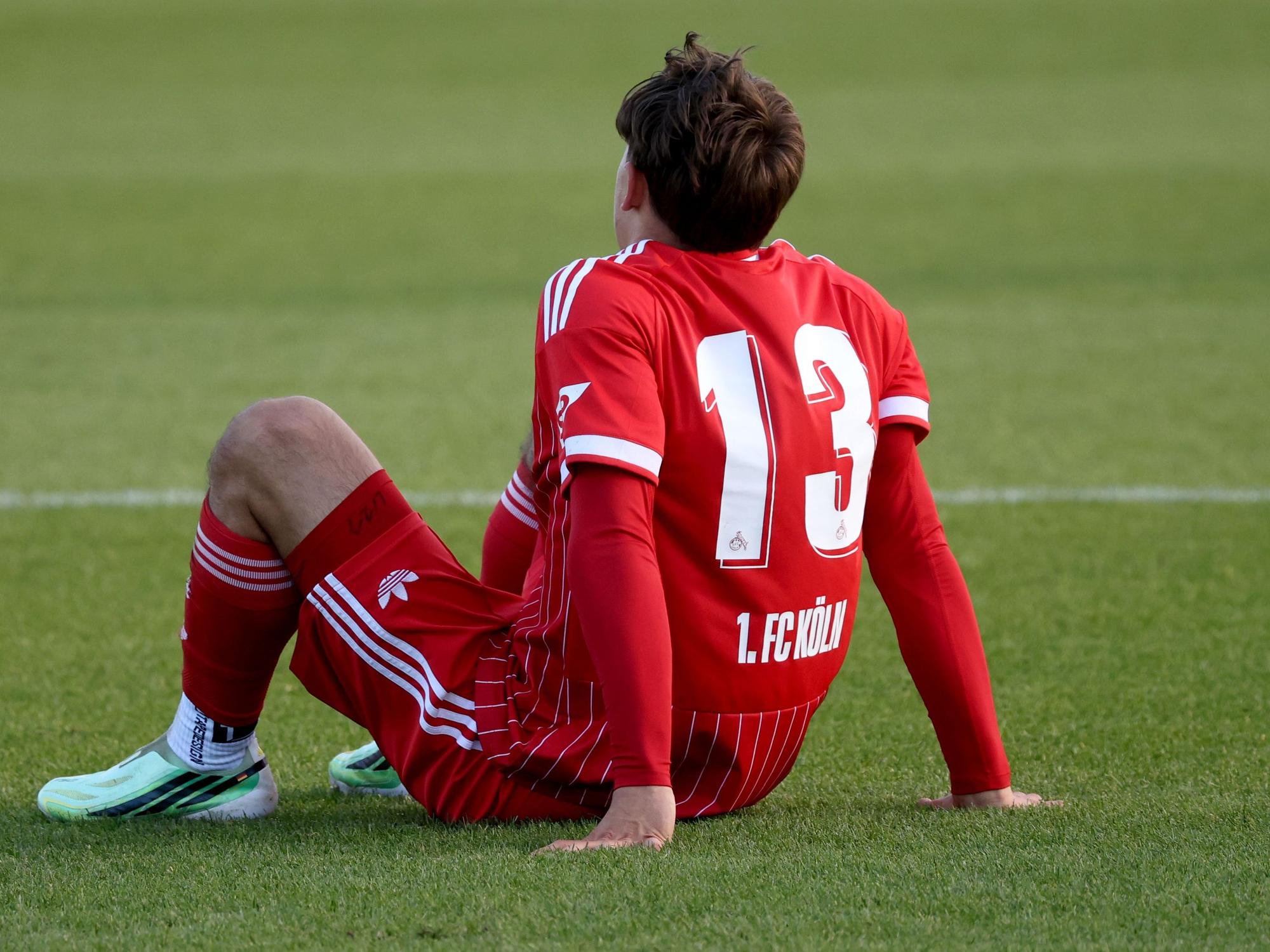 Cenny Neumann s (13) von Köln beim U23 Fußball Regionalliga-West Spiel zwischen FC Schalke 04 und dem 1.FC Köln sitzt verletzt auf dem Rasen.