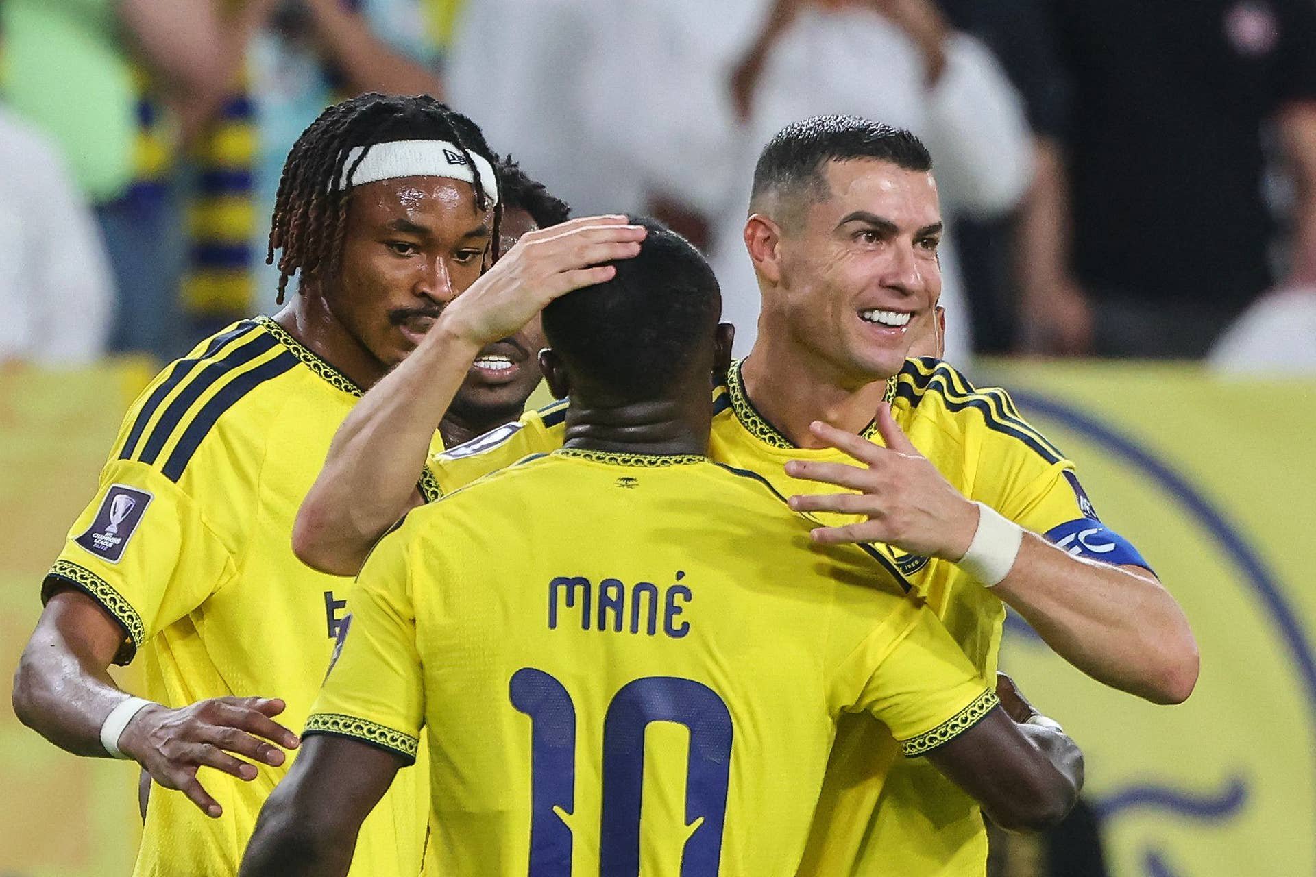 Cristiano Ronaldo gratuliert gemeinsam mit Teamkollegen Sadio Mané im gelben Al-Nassr-Trikot freudestrahlend zu einem Treffer auf dem Spielfeld.
