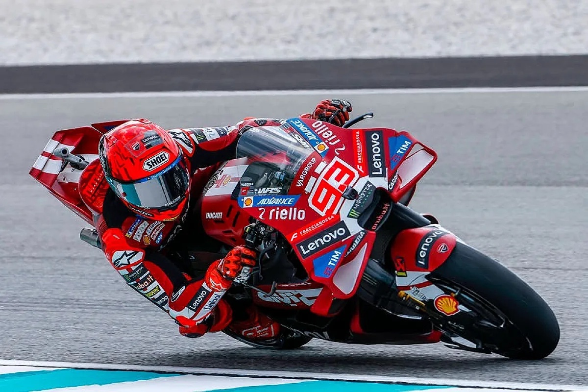 A rider in red Ducati leathers and helmet leans into a corner on a red Ducati MotoGP bike with Lenovo and Riello livery at Sepang