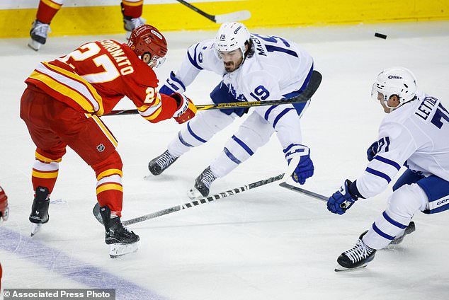 Toronto Maple Leafs' Zack MacEwen, center, and Vinni Lettieri, right, check Calgary Flames' Matt Coronato as he flips the puck past them during the second period of an NHL hockey game in Calgary, Alberta, Monday, Oct. 26, 2026. (Jeff McIntosh/The Canadian Press via AP)