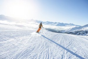 Eine Person fährt mit Skiern einen Hang hinab.