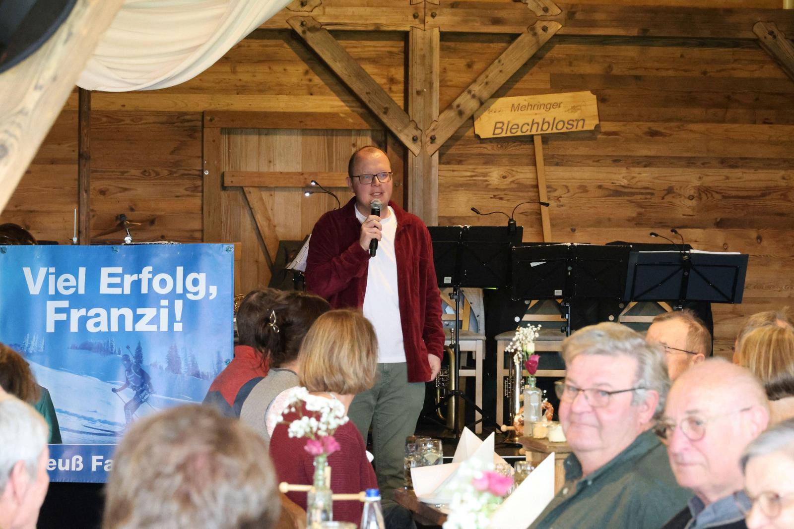 Sebastian Friesinger, Vorsitzender des Franziska Preuß Fanclubs, spricht mit einem Mikrofon auf der Abschlussfeier vor Publikum.