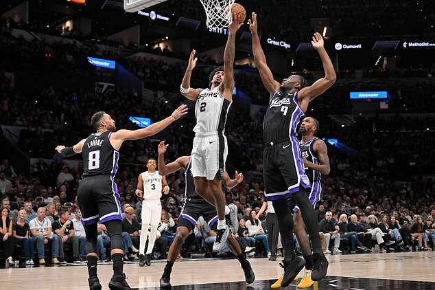 San Antonio Spurs guard Dylan Harper (2) goes to the basket against Sacramento Kings' Precious Achiuwa (9) and Zach LaVine (8) during the first half of an NBA basketball game, Tuesday, Oct. 27, 2026, in San Antonio. (AP Photo/Darren Abate)