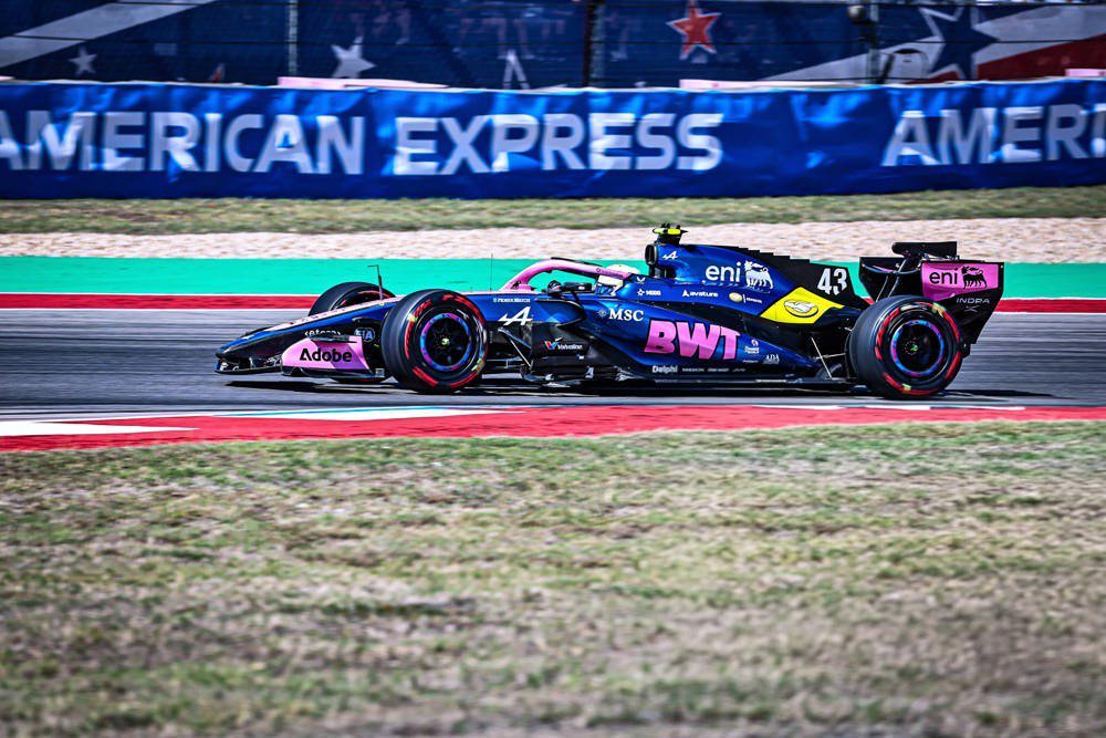 Alpine F1 car number 43 with BWT livery on track, Franco Colapinto's team car at a US circuit, American Express barriers behind.