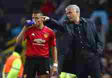 Jose Mourinho points out instructions to Alexis Sanchez while the latter drinks from a bottle at the edge of the Old Trafford pitch.
