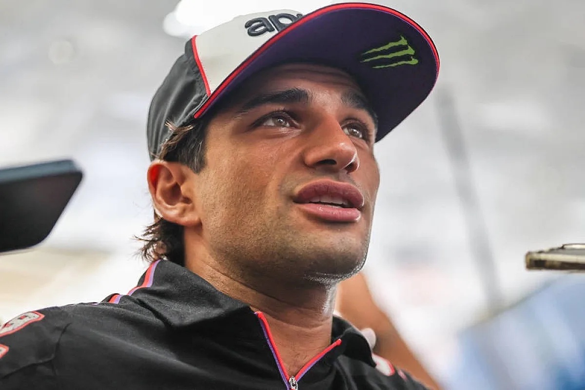 A rider in a black and white Aprilia-style cap and black jacket speaks to reporters in the MotoGP paddock after withdrawing from the Malaysian Grand Prix.