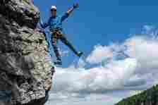 woman hanging on a cliff edge via ferrata