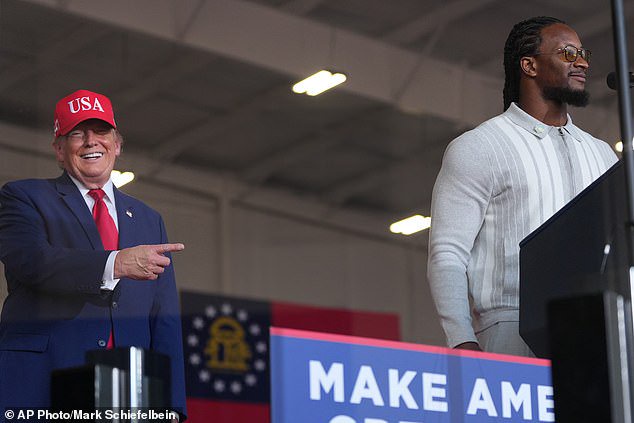Donald Trump listens as Todd Gurley speaks at a campaign rally at Dalton Municipal Airport
