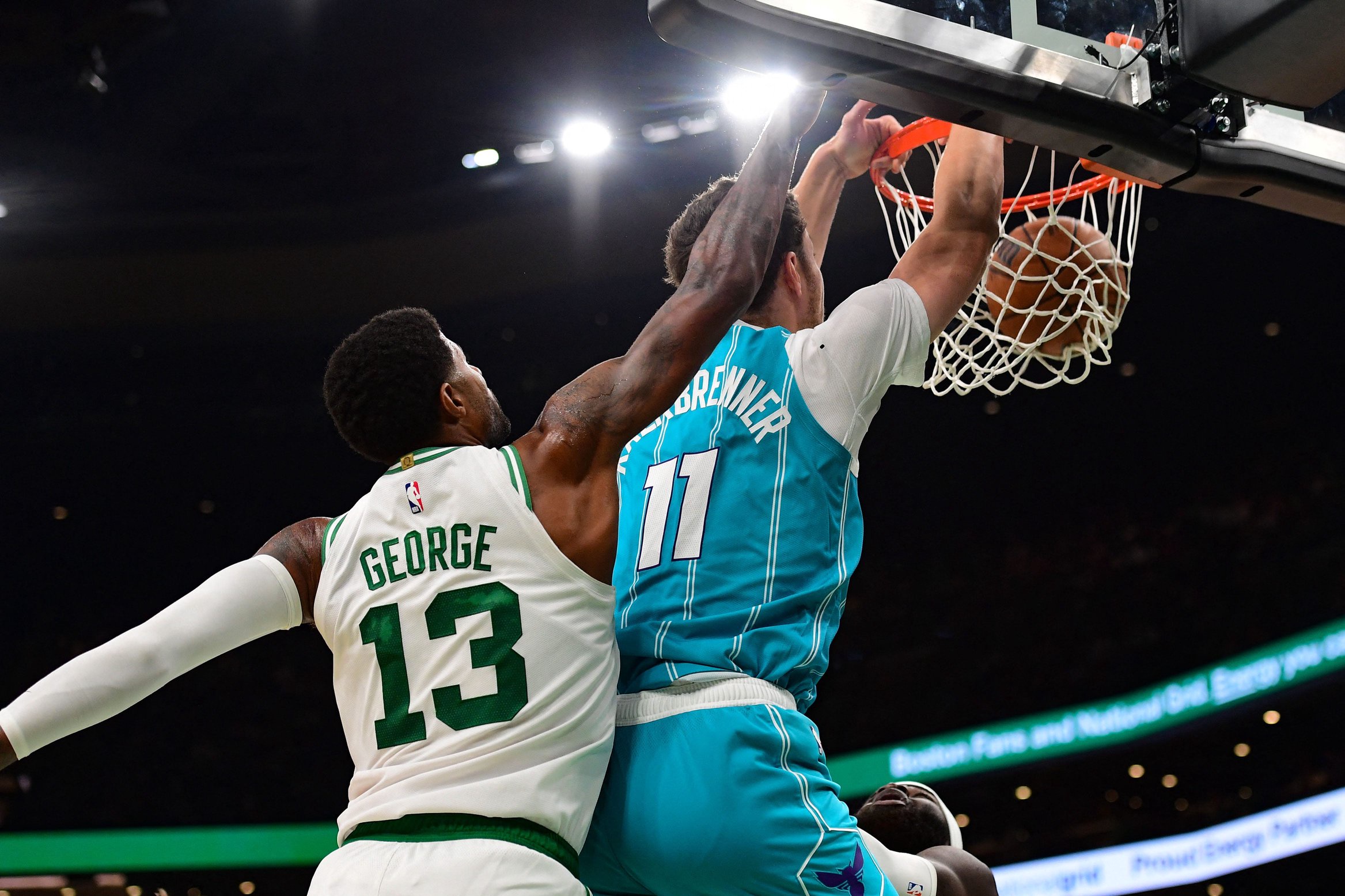 Oct 14, 2026; Boston, Massachusetts, USA;  Charlotte Hornets center Ryan Kalkbrenner (11) dunks the ball past Boston Celtics forward Paul George (13) during the second half at TD Garden. Mandatory Credit: Bob DeChiara-Imagn Images