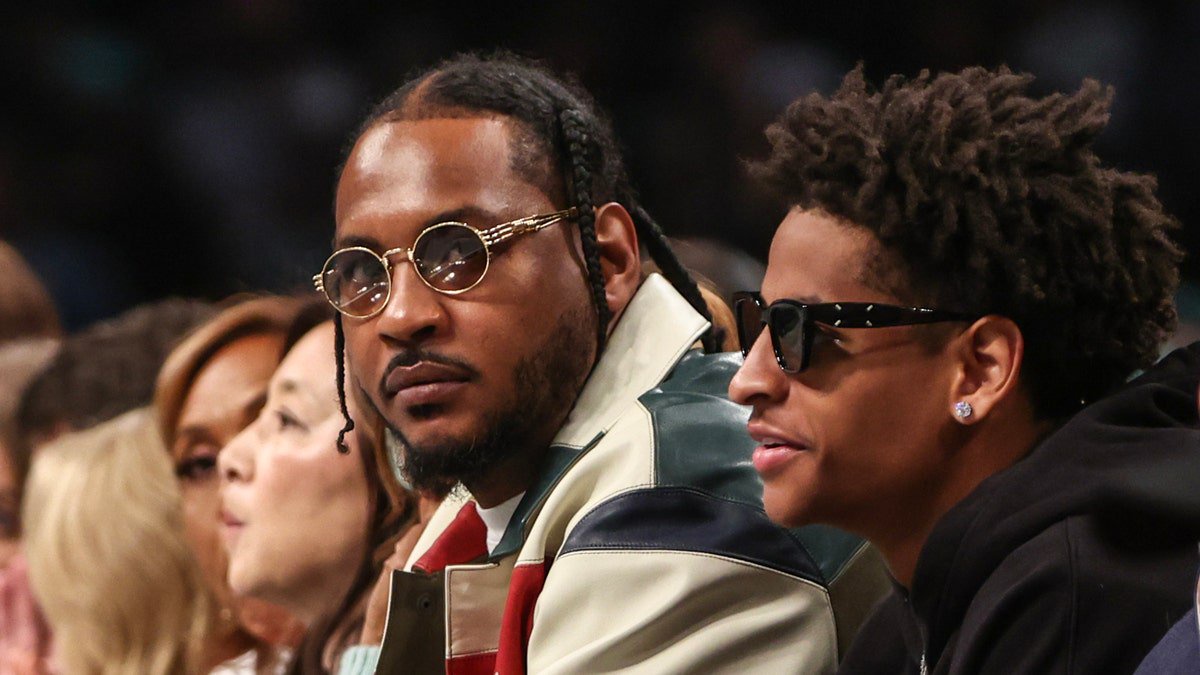 Carmelo Anthony and his son, Kiyan, look on at a basketball game