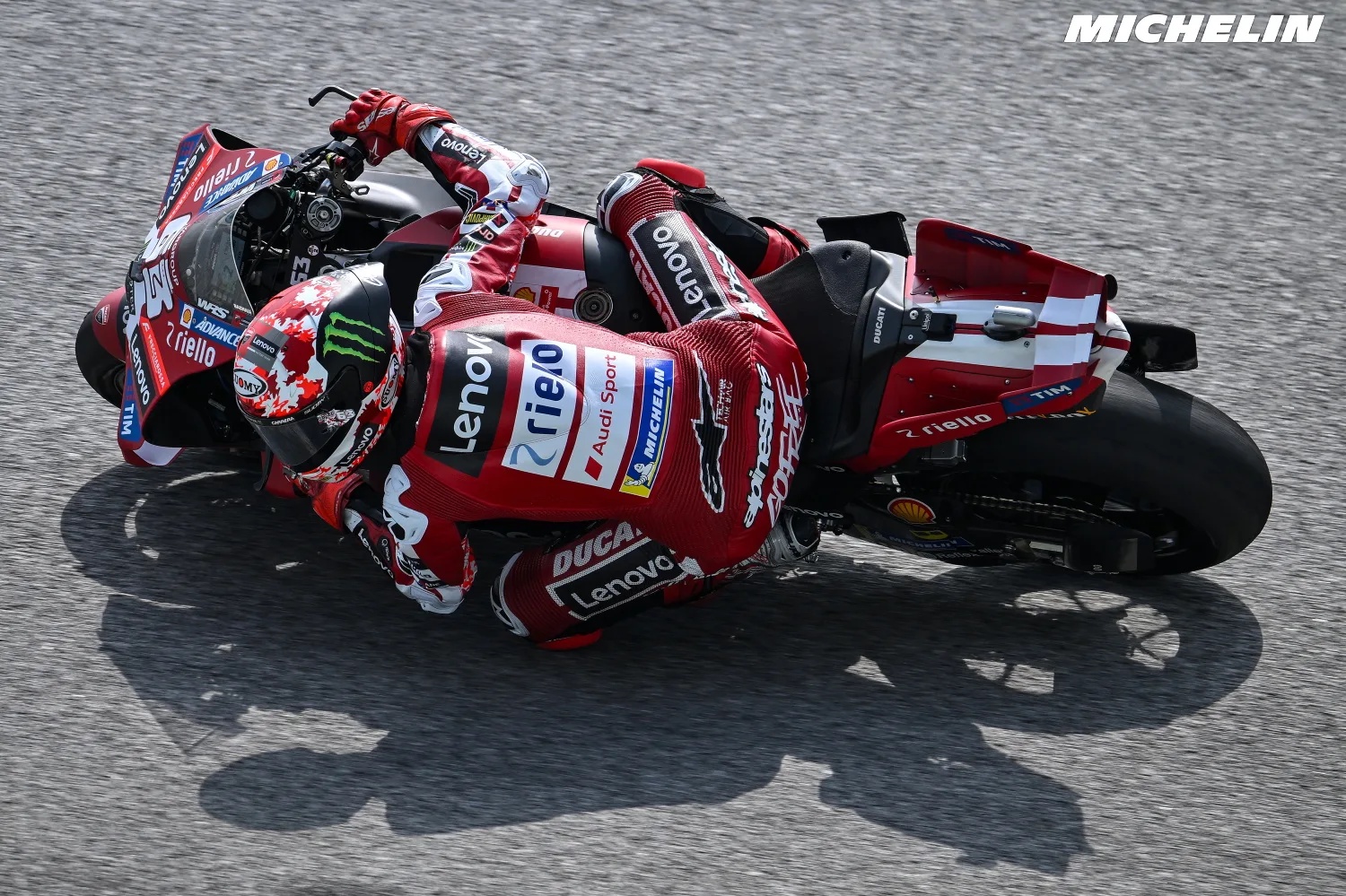 Ducati rider in red Ducati Lenovo leathers leaning hard through a corner on a red Ducati MotoGP bike, Sepang circuit