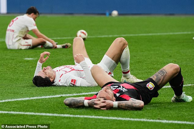 Leverkusen's Aleix Garcia and Freiburg's Igor Matanovic lie exhausted on the pitch after the German Bundesliga soccer match between Bayer Leverkusen and SC Freiburg in Leverkusen, Germany, Sunday, Oct. 18, 2026. (AP Photo/Martin Meissner)