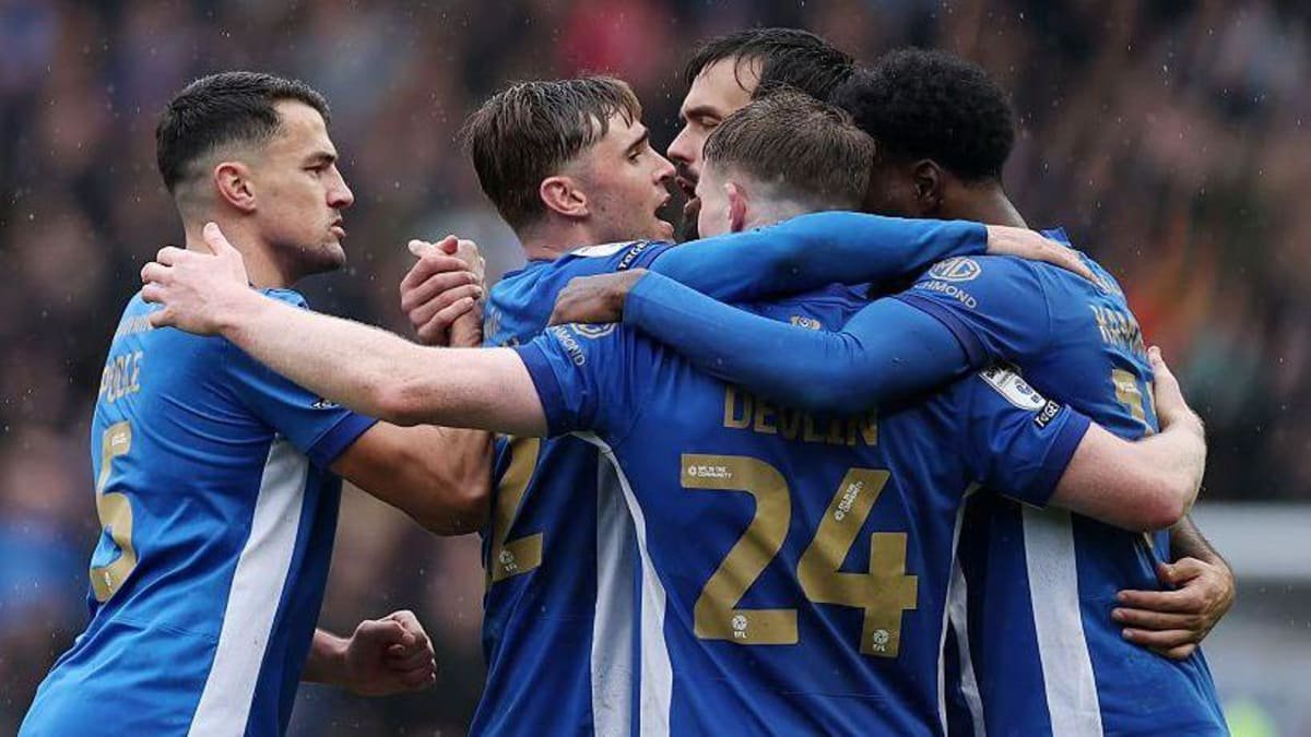Portsmouth players embrace to celebrate victory over Millwall