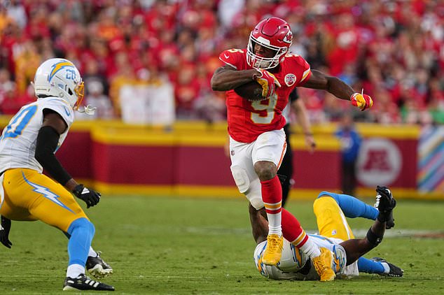 Kansas City Chiefs running back Kenneth Walker III (9) escapes a tackle attempt by Los Angeles Chargers linebacker Del'shawn Phillips, bottom, as Cam Hart (20) moves in to make this stop during the second half of an NFL football game in Kansas City, Mo., Sunday, Oct. 18, 2026. (AP Photo/Ed Zurga)