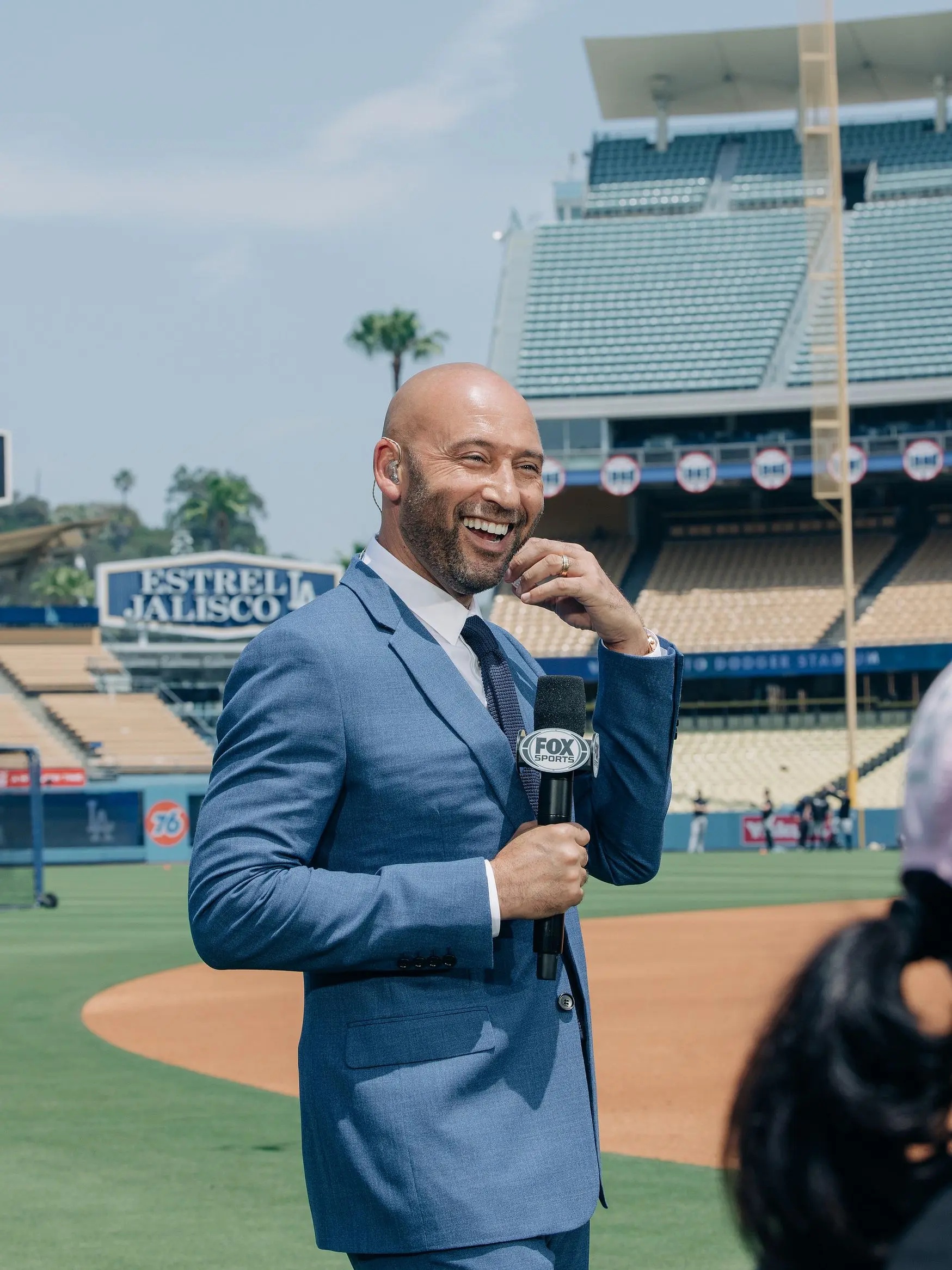 Derek Jeter smiles while holding a Fox Sports microphone.