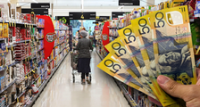 Woman walking down supermarket aisle next to wad of $50 notes