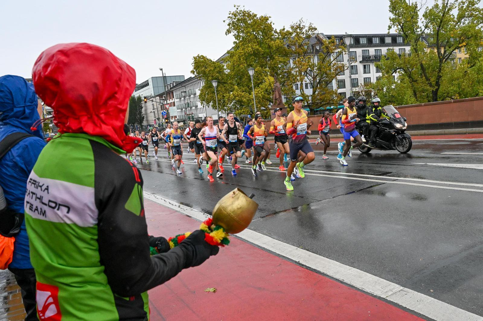 Der erste Teil der Laufstrecke in stroemendem Regen. Zuschauer auf der Alten Bruecke mit Schirmen und wetterfester Kleidung feuern die Laeufer an.