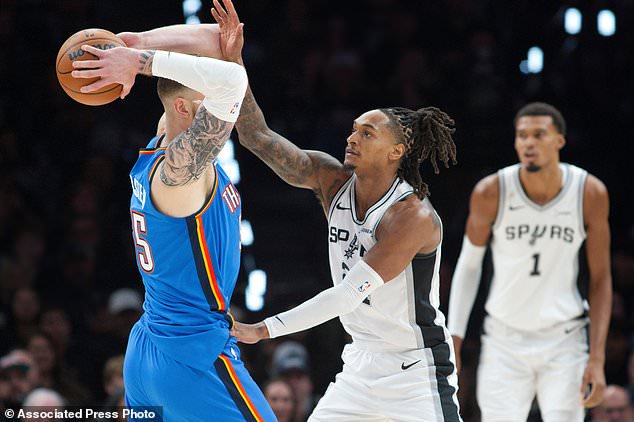 Oklahoma City Thunder center Isaiah Hartenstein, left, looks to pass as he is guarded by San Antonio Spurs guard Devin Vassell during the first half of an NBA basketball game, Tuesday, Oct. 20, 2026, in San Antonio. (AP Photo/Darren Abate)