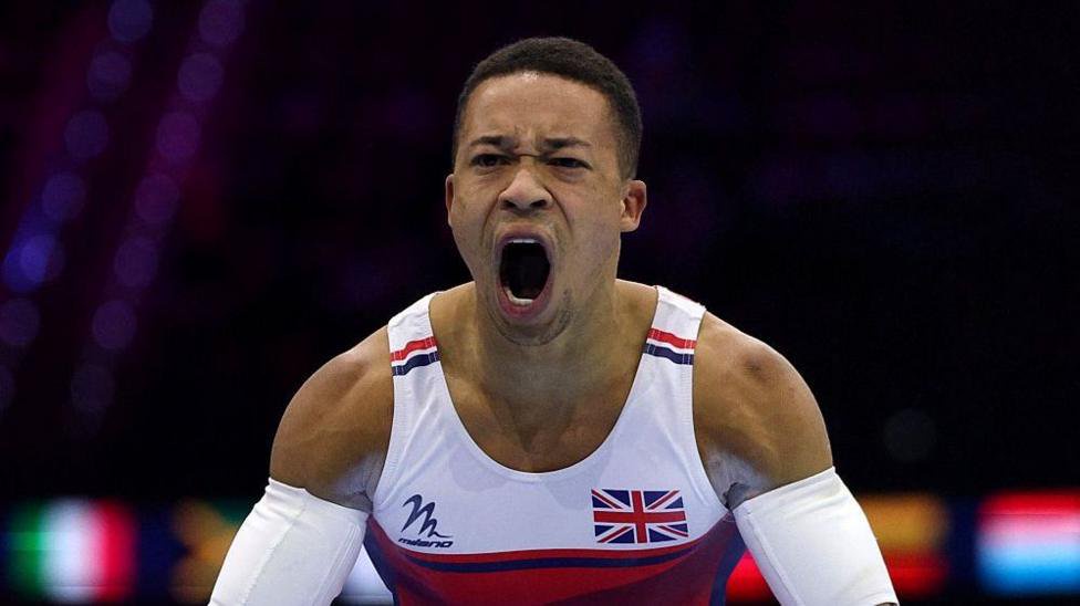 Joe Fraser with his mouth wide open and a passionate expression on his face as he competes in Great Britain kit, with strapping on both arms
