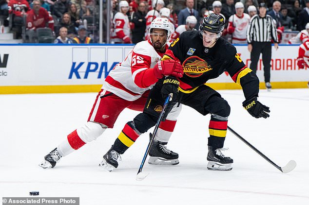 Detroit Red Wings' Keegan Kolesar (55) and Vancouver Canucks' Zeev Buium (8) vie for the puck during the second period of an NHL hockey game in Vancouver, British Columbia, Thursday, Oct. 22, 2026. (Ethan Cairns/The Canadian Press via AP)