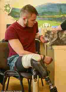 Sasha, who lost both his legs to an explosion in the Donbas, pets five-year-old Persian-Siberian cross therapy cat Boss who helps traumatised Ukrainian soldiers with their mental recovery