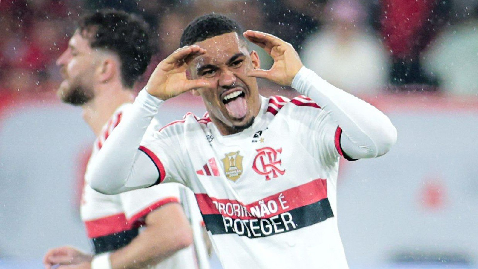 Jogador Pedro em camisa do Flamengo celebra, língua para fora, mãos no rosto. Texto 'ROBINA É POTEGER'