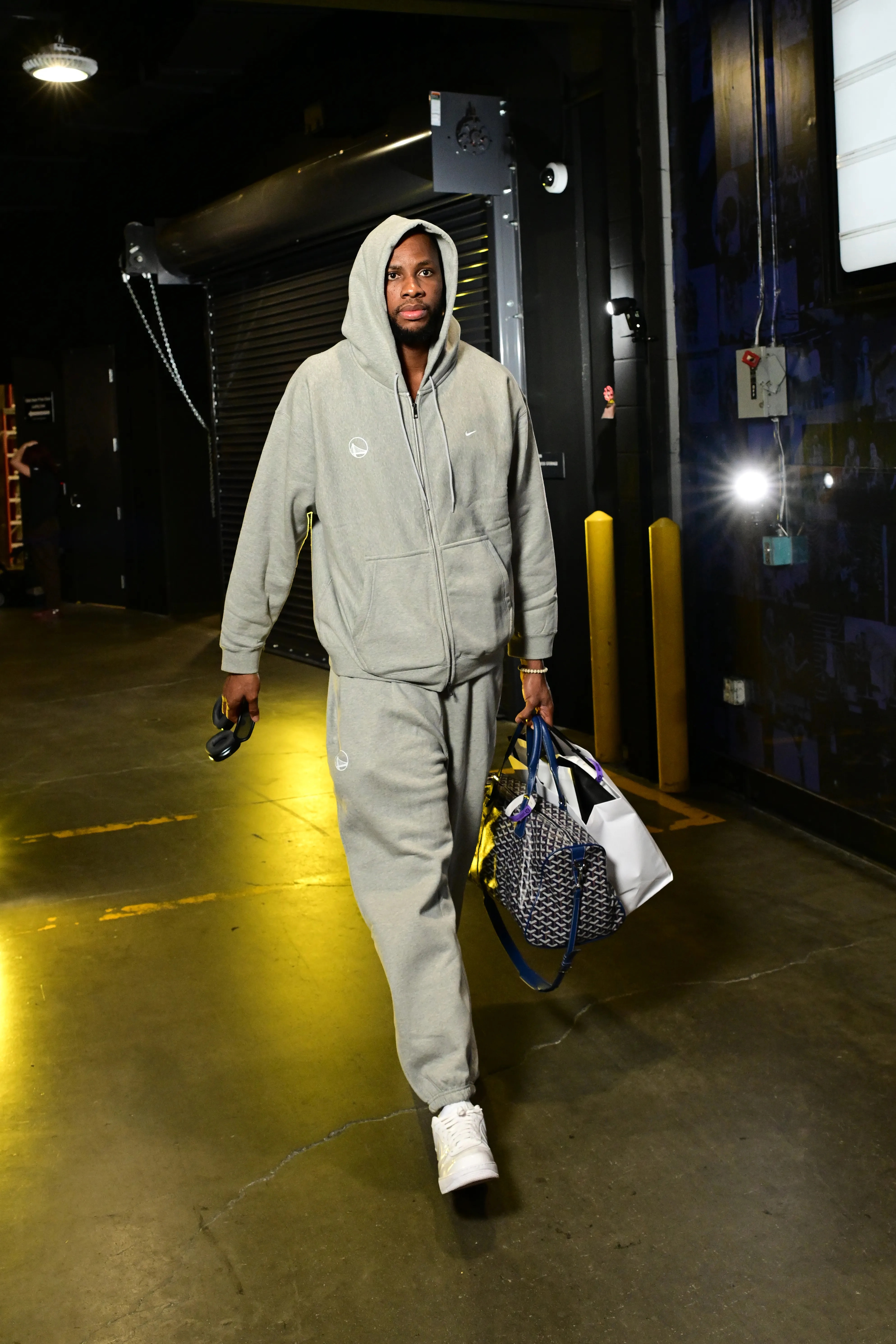 Charles Bassey of the Golden State Warriors arrives to the arena wearing a gray tracksuit and carrying bags.