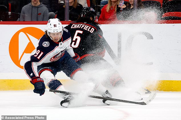 Columbus Blue Jackets' Kent Johnson (91) gets knocked off the puck by Carolina Hurricanes' Jalen Chatfield (5) during the first period of an NHL hockey game in Raleigh, N.C., Thursday, Oct. 29, 2026. (AP Photo/Karl DeBlaker)