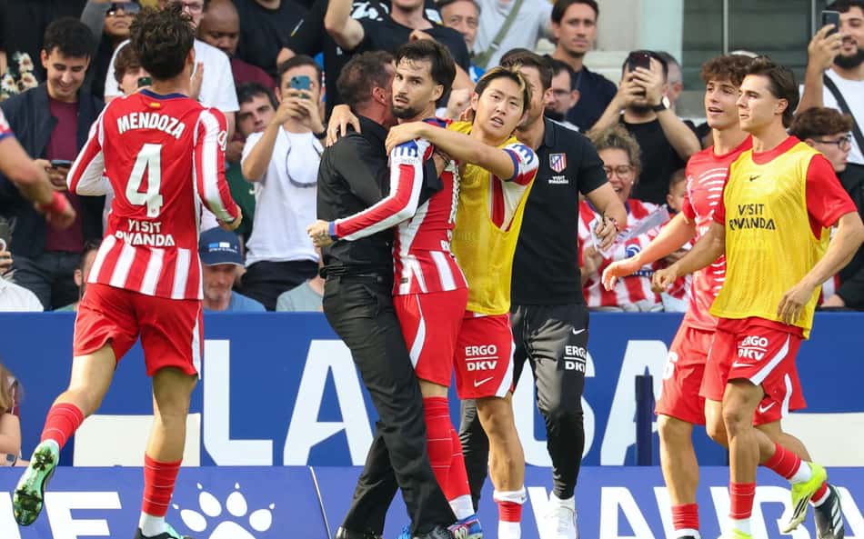 Jogadores do Atlético de Madrid se abraçam, torcedores ao fundo.