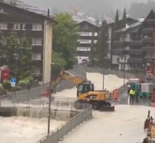 An excavator was seen on a bridge as violent floods run below it