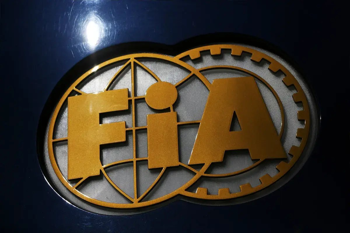 Close-up of the gold FIA (Fédération Internationale de l'Automobile) logo on a dark blue background, the governing body of Formula 1