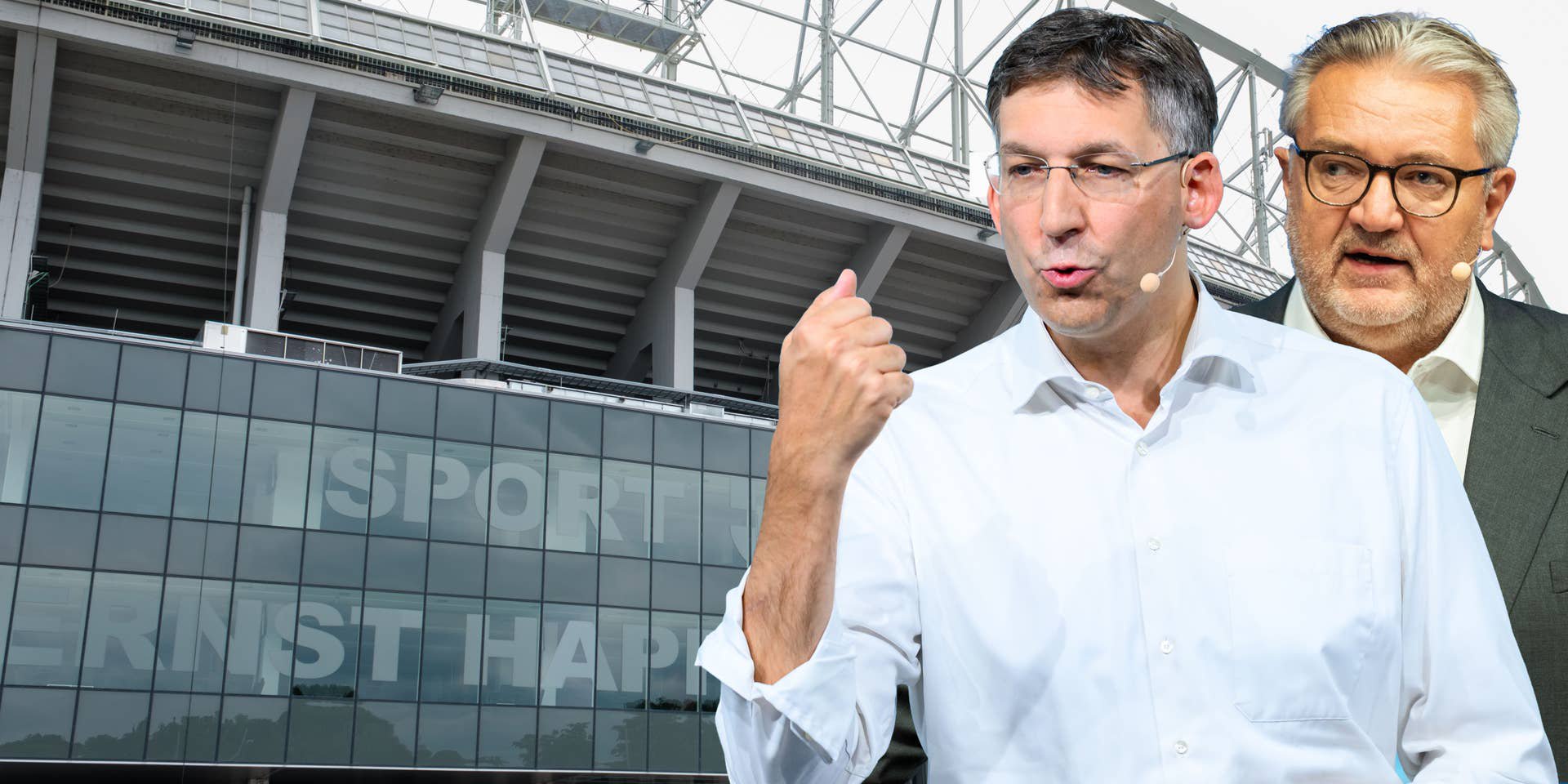 Zwei Männer mit Mikrofonen vor einem modernen Stadion-Gebäude.