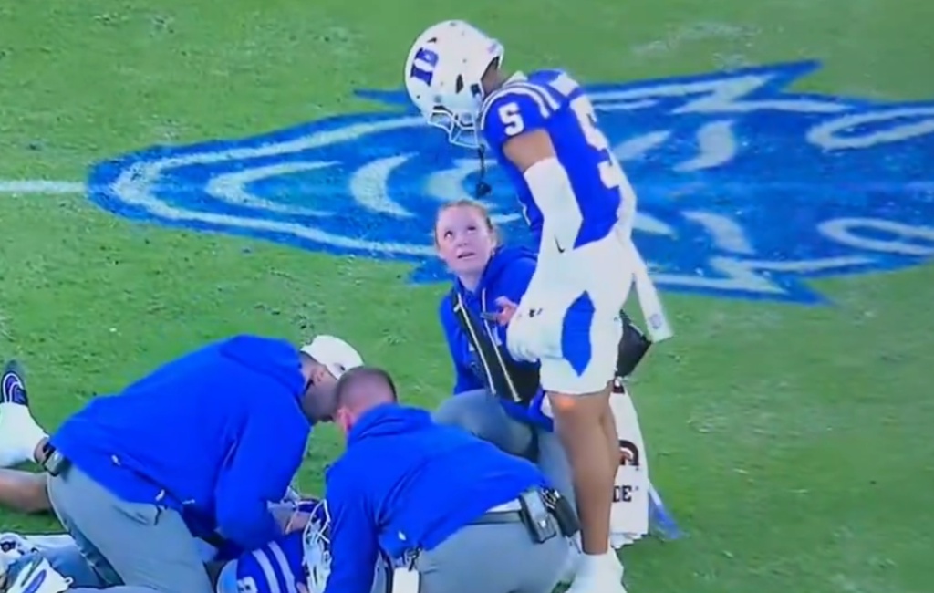 Medical staff and a player attend to an injured football player on the field.