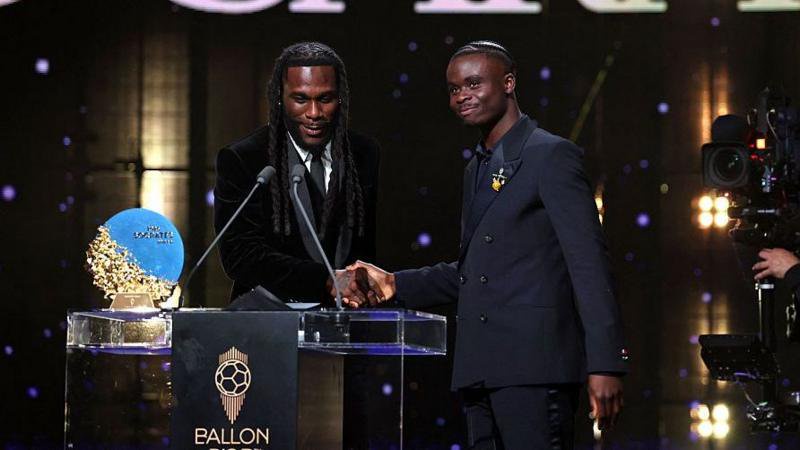 Nigerian singer Burna Boy presents the Socrates Trophy for most involved player in societal and charitable projects to English fooballer Bukayo Saka