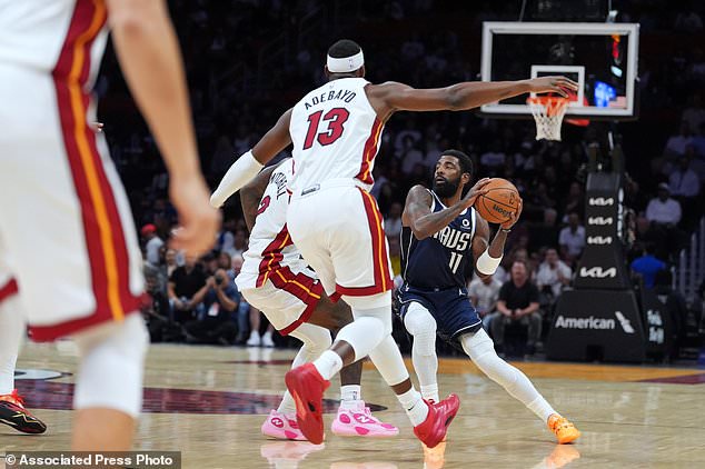 Dallas Mavericks guard Kyrie Irving (11) looks for an opening defended by Miami Heat guard Davion Mitchell (2) and center Bam Adebayo (13) during the first half of an NBA basketball game, Monday, Oct. 26, 2026, in Miami. (AP Photo/Rebecca Blackwell)