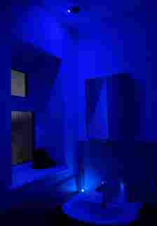 A W-Charge transmitter in the ceiling and a AirCord-enabled toothbrush in a bathroom showing a blue light in a bathroom with a blue light indicated the connection between them.