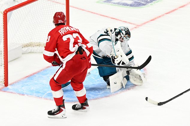 San Jose Sharks goaltender Alex Nedeljkovic, right, blocks a shot attempt from Detroit Red Wings left wing Lucas Raymond during the first period of an NHL hockey game, Saturday, Oct. 17, 2026, in Detroit. (AP Photo/Jose Juarez)