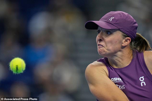 Iga Swiatek, of Poland, eyes an incoming ball from Elise Mertens, of Belgium during the quarterfinals of the women's singles match at the China Open tennis tournament in Beijing, Friday, Oct. 9, 2026.. (AP Photo/Andy Wong)