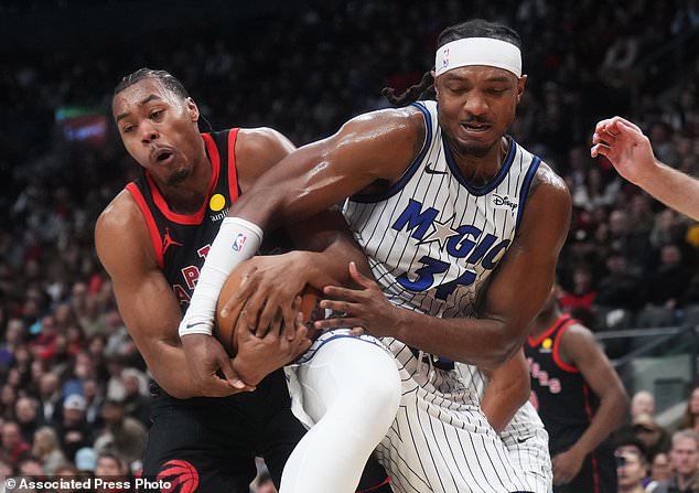 Toronto Raptors' Scottie Barnes (left) and Orlando Magic's Wendell Carter Jr. (34) battle for the ball during the first half of an NBA Cup basketball game in Toronto, Friday, Oct. 30, 2026. (Nathan Denette/The Canadian Press via AP)